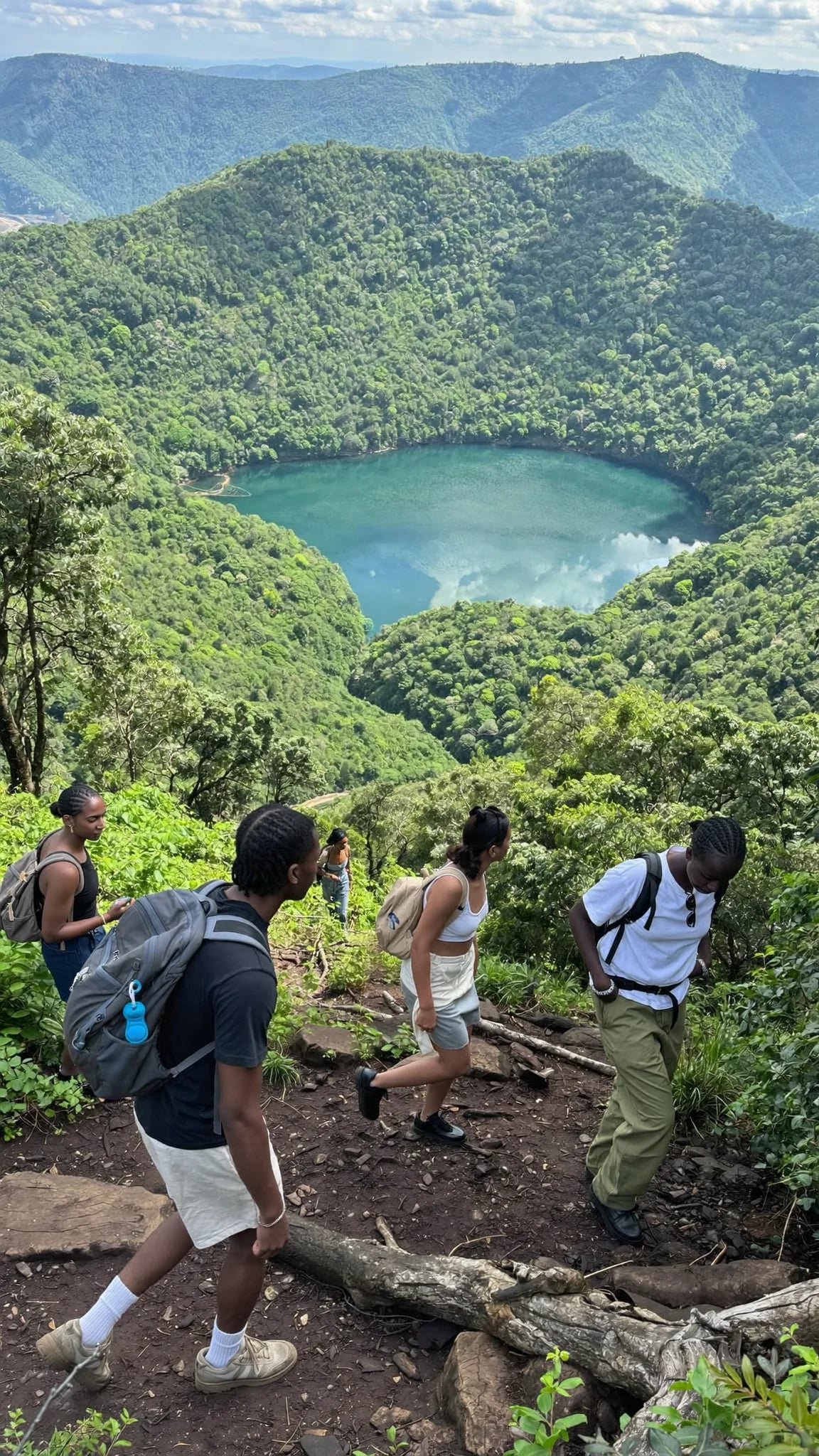 A group walking together outdoors dressed in white clothing and woven shawls, one woman smiling.